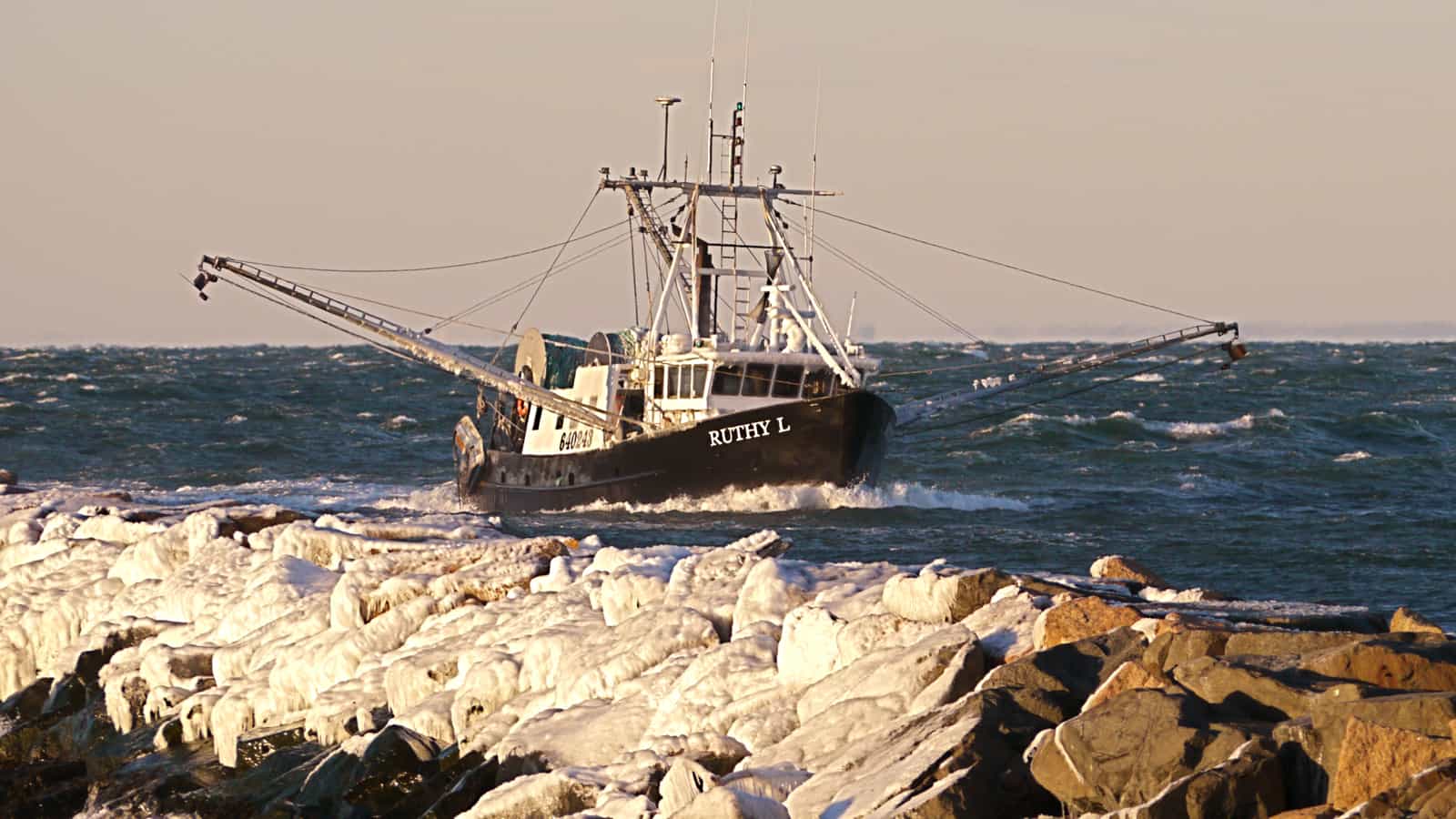 The trawler Ruthy L coming into Montauk Harbor on a bitterly cold January day. Ice on the jetty in the foreground.